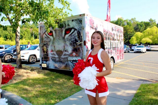 Image of Sasha in a cheerleading uniform and pompoms