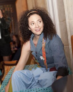 Portrait of Erika Diamond in a denim, one sleeve top. She is smiling and looking somewhere off camera. 